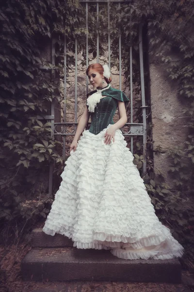 Uma mulher como uma princesa em um vestido vintage no parque de fadas — Fotografia de Stock