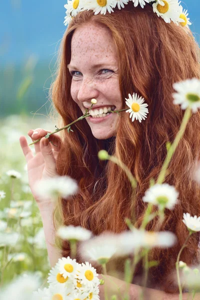 Beautiful red-haired girl with freckles and a camomile in a mout — 图库照片