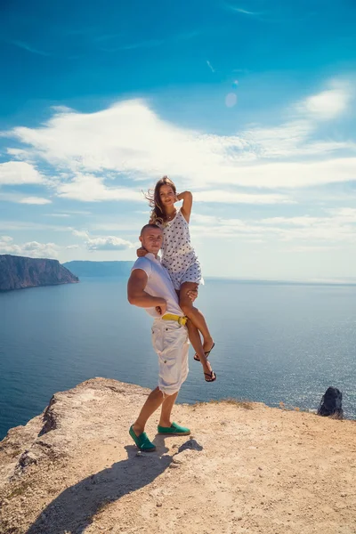 Bir uçurumun üstünde mavi deniz üzerinde çift duruyor — Stok fotoğraf