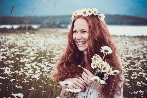 Imagem da mulher bonita deitada no campo de camomila, feliz fêmea segurando na mão bela flor branca, menina alegre descansando no prado margarida, relaxamento ao ar livre na primavera, conceito de férias — Fotografia de Stock