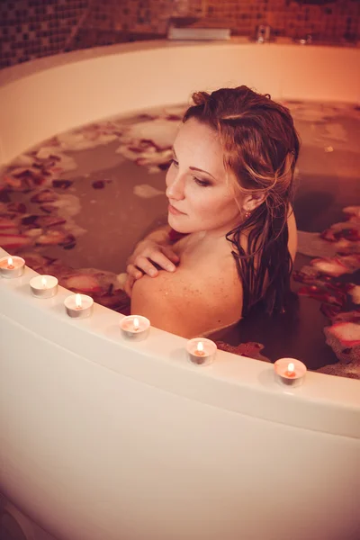 Mujer joven con el pelo rojo tomar baño de burbujas con vela . — Foto de Stock