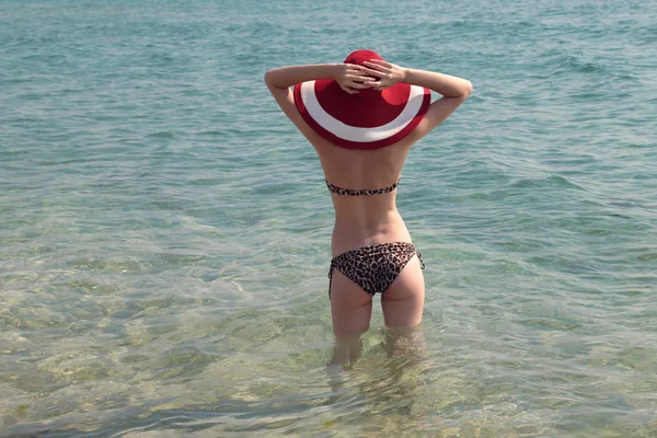 Strandurlaub. heiße schöne Frau in Sonnenhut und Bikini steht mit erhobenen Armen auf dem Kopf und genießt den Blick auf den Strand Ozean an heißen Sommertagen. — Stockfoto