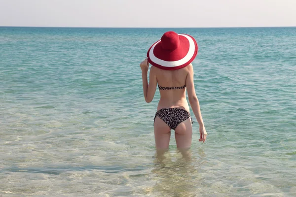 As férias na praia. Mulher bonita quente de chapéu de sol e biquíni de pé com os braços erguidos na cabeça desfrutando de vista para o oceano de praia no dia quente de verão . — Fotografia de Stock