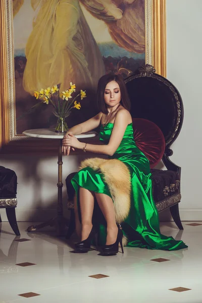 Módní fotografie nádherné ženy s tmavými vlasy v elegantní zelené hedvábné šaty, pózuje v luxusním interiéru — Stock fotografie