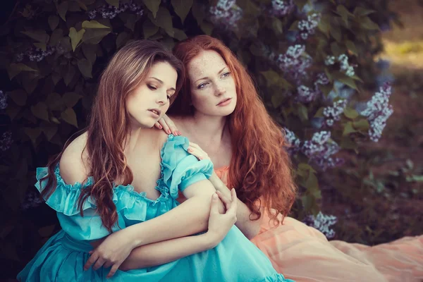 Hermosas mujeres disfrutando de jardín lila, mujeres jóvenes con flores — Foto de Stock