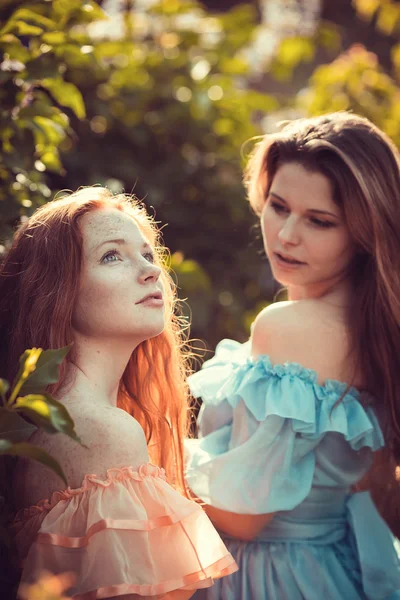 Mooie vrouwen genieten van lila Tuin, jonge vrouwen met bloemen — Stockfoto