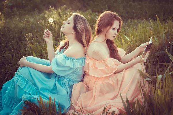 Hermosas mujeres disfrutando de jardín lila, mujeres jóvenes con flores — Foto de Stock