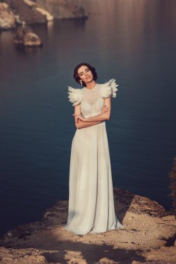 Güzel gelin melek elbise ile sahilde poz
