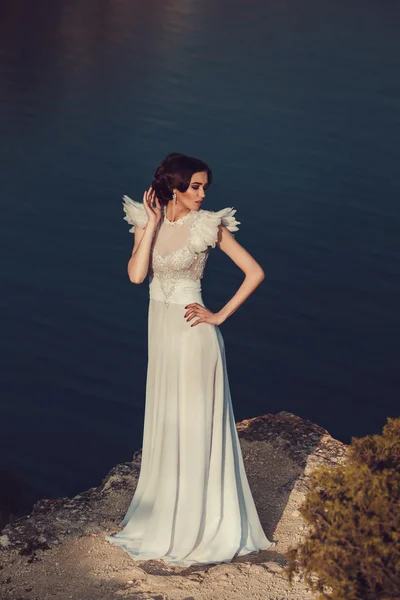 Beautiful bride posing on the coast with angelic dress — Stock Photo, Image