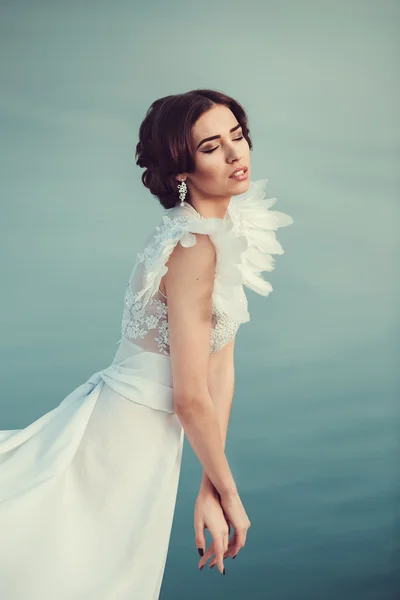 Bella sposa in posa sulla costa con abito angelico — Foto Stock