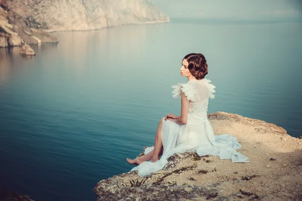 Mooie bruid poseren aan de kust met engelachtige jurk — Stockfoto