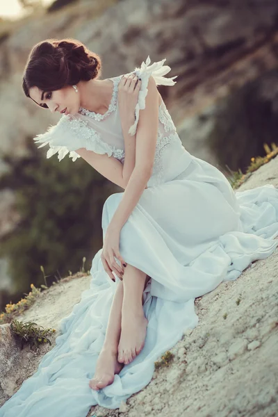 Beautiful bride posing on the coast with angelic dress — Stock Photo, Image