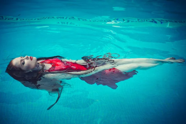 Mujer sexy joven flotando en la piscina en vestido rojo. tiro de belleza —  Fotos de Stock