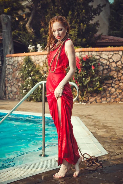 Mujer sexy joven flotando en la piscina en vestido rojo . — Foto de Stock