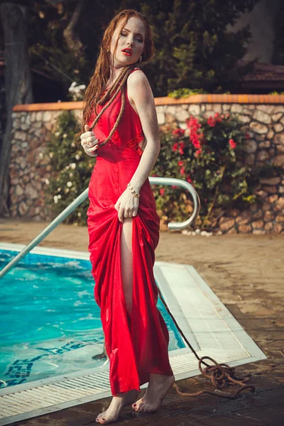 Mujer sexy joven flotando en la piscina en vestido rojo . — Foto de Stock