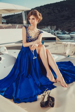 Beautiful young sexy girl in a dress and makeup, summer trip on a yacht with white sails on the sea or ocean