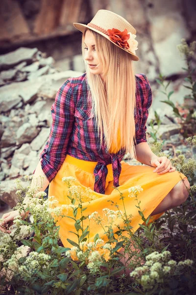 Vacker blond flicka i en hatt, pläd skjorta och klänning i naturen — Stockfoto