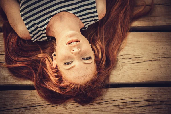 Beautiful sexy woman is dressed in a sea stripped vest sits on the seashore dreams. — Stock Photo, Image