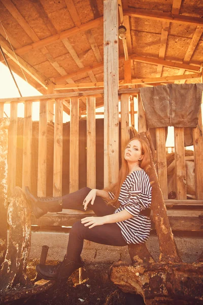 Beautiful sexy woman is dressed in a sea stripped vest sits on the seashore dreams. — Stock Photo, Image