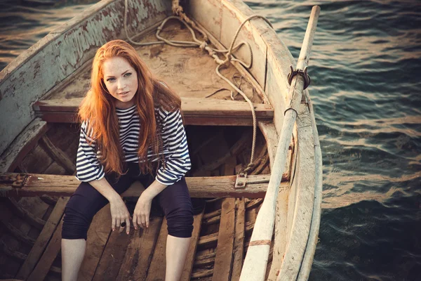 Hermosa sexy mujer es vestida en un mar despojado chaleco se sienta en la orilla del mar sueños . — Foto de Stock