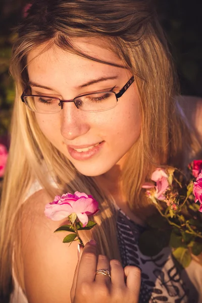 Mulher bonita no jardim com rosas ao pôr do sol — Fotografia de Stock