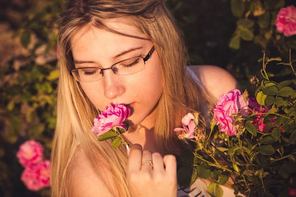 Belle femme dans le jardin avec des roses au coucher du soleil — Photo