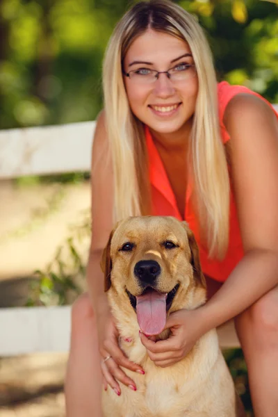 Portret van mooi jong meisje met haar hond labrador retriever buiten in de zomer prachtig park — Stockfoto