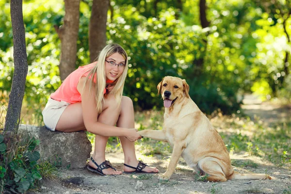 Portret van mooi jong meisje met haar hond labrador retriever buiten in de zomer prachtig park — Stockfoto