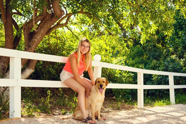 Portret van mooi jong meisje met haar hond labrador retriever buiten in de zomer prachtig park — Stockfoto