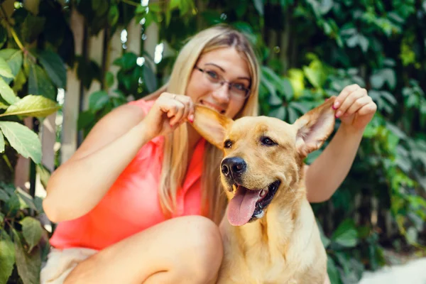 Portret van mooi jong meisje met haar hond labrador retriever buiten in de zomer prachtig park — Stockfoto