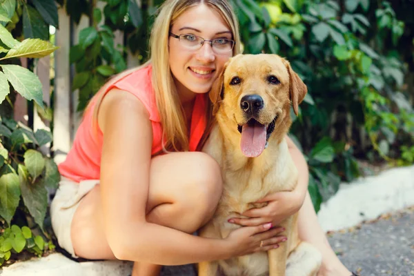 Portret van mooi jong meisje met haar hond labrador retriever buiten in de zomer prachtig park — Stockfoto