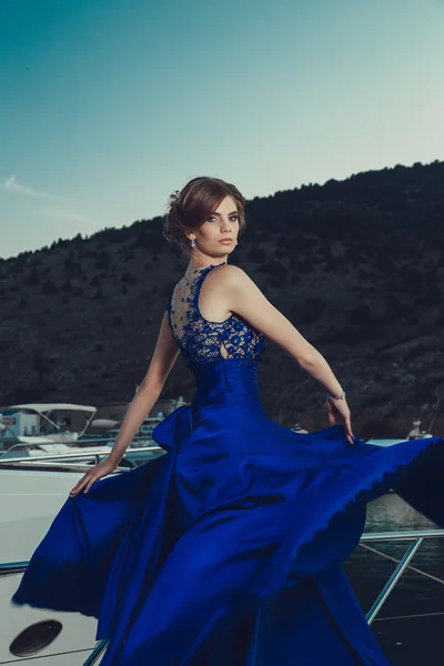 Beautiful young sexy girl in a dress and makeup, summer trip on a yacht with white sails on the sea or ocean — Stock fotografie