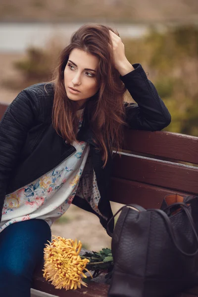 Beautiful young smiling brunette woman with flowers in autumn park — Stock Photo, Image