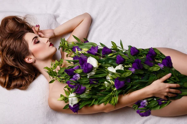 Fashion studio photo of beautiful brunette woman with bright makeup with a bouquet of purple and white eustoma — Stock Photo, Image