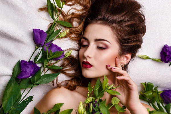 Fashion studio photo of beautiful brunette woman with bright makeup with a bouquet of purple and white eustoma — Stock Photo, Image