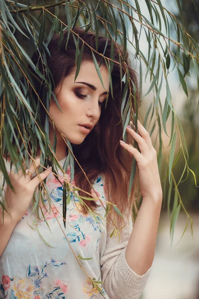 Belle jeune femme brune souriante avec des fleurs dans le parc d'automne — Photo