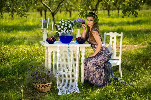 La fille est assise à une table dans le jardin Images De Stock Libres De Droits