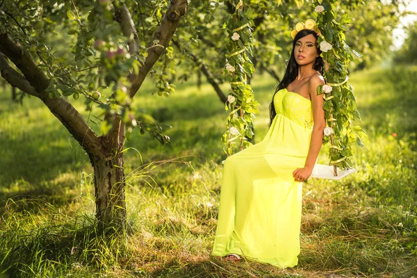 Mädchen auf einer Schaukel in einem gelben Kleid — Stockfoto