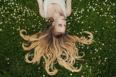 Güzel kız çimlerin üzerinde yatıyor.