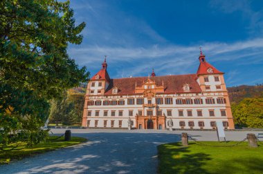Renkli sonbahar renkleri, parktaki parlak mavi gökyüzü ve Graz, Styria bölgesindeki Eggenberg Sarayı, Avusturya
