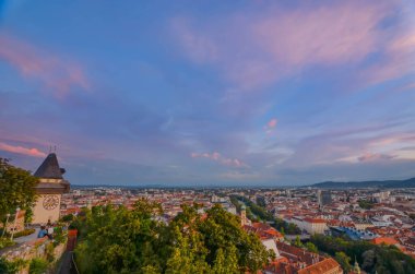 Graz, Avusturya - 30 Ağustos 2020: Graz şehri ve Schlossberg tepesindeki ünlü saat kulesi, Graz, Styria bölgesi, gün batımında