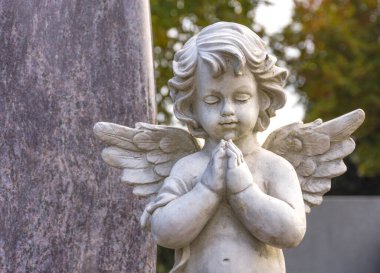 Mezarlıktaki bir mezarda küçük bir melek heykeli. Seçici odak
