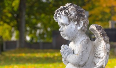 Mezarlıktaki bir mezarda küçük bir melek heykeli. Seçici odak