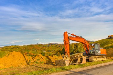 Turuncu kazıcı / kazıcı makinesi, bakım için üzüm bağlarını kazıyor ya da sonbaharda Avusturya 'nın Güney Styria kentinde yeni ekime hazırlıyor.