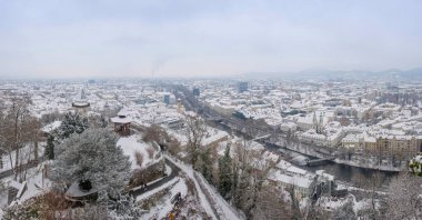 Schlossberg tepesindeki ünlü saat kulesi ve karlı tarihi binalar, Graz, Styria bölgesi, Avusturya, kış günü