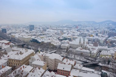 Mariahilfer kilisesi ile Graz şehri ve Graz, Styria bölgesinin tarihi ve modern binaları, kışın karlı.