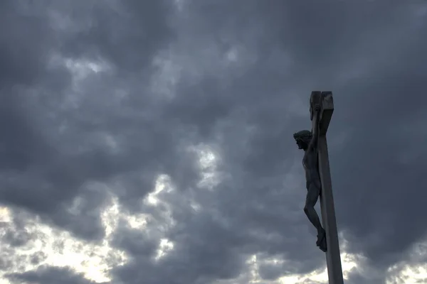 Jesus Christ on the cross against dramatic cloudy sky, at sunset. Crucifixion, religion and spirituality