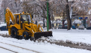 Yellow tractor with snowplow removing snow from the streets.
