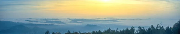 Amazing foggy sunrise over the city of Graz with Schlossberg hill and Church of the Sacred Heart of Jesus tower, in Styria region, Austria. Panoramic view from Plabutsch mountain on autumn morning.