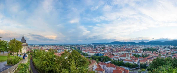 Graz şehri ve saat kulesi (Grazer Uhrturm), Shlossberg Hill, Graz, Styria bölgesi, Avusturya 'da gün batımında ünlü turistik ilgi odağı. Dramatik gökyüzü, panoramik manzara